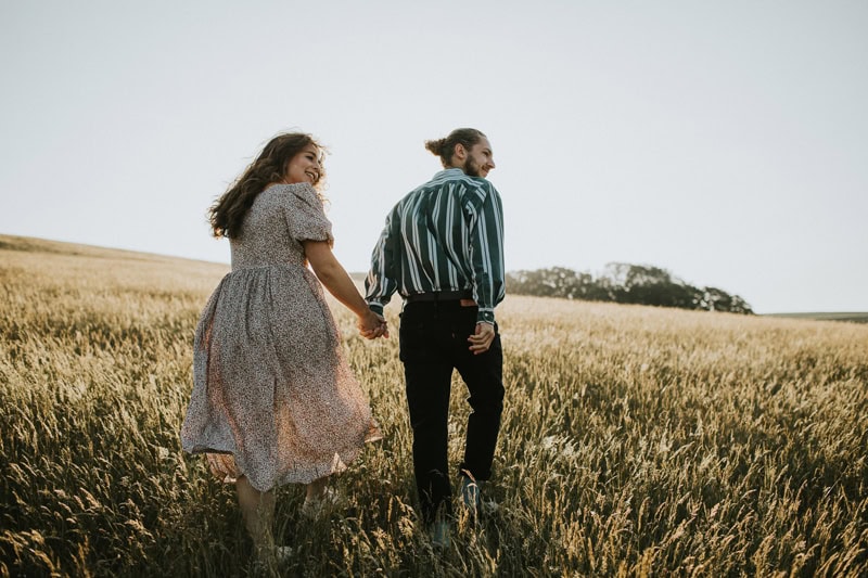 Kent Wedding Photographer, a couple, man and woman, walk through a golden field together